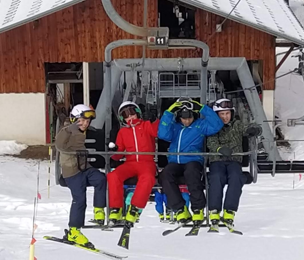 Enfants et jeunes sur un télésiège en camp de vacances ski.